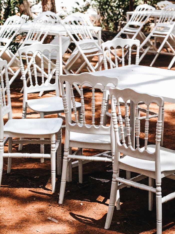 hero-img-02 Rustic outdoor scene featuring white chairs arranged for an event on a sunny day.